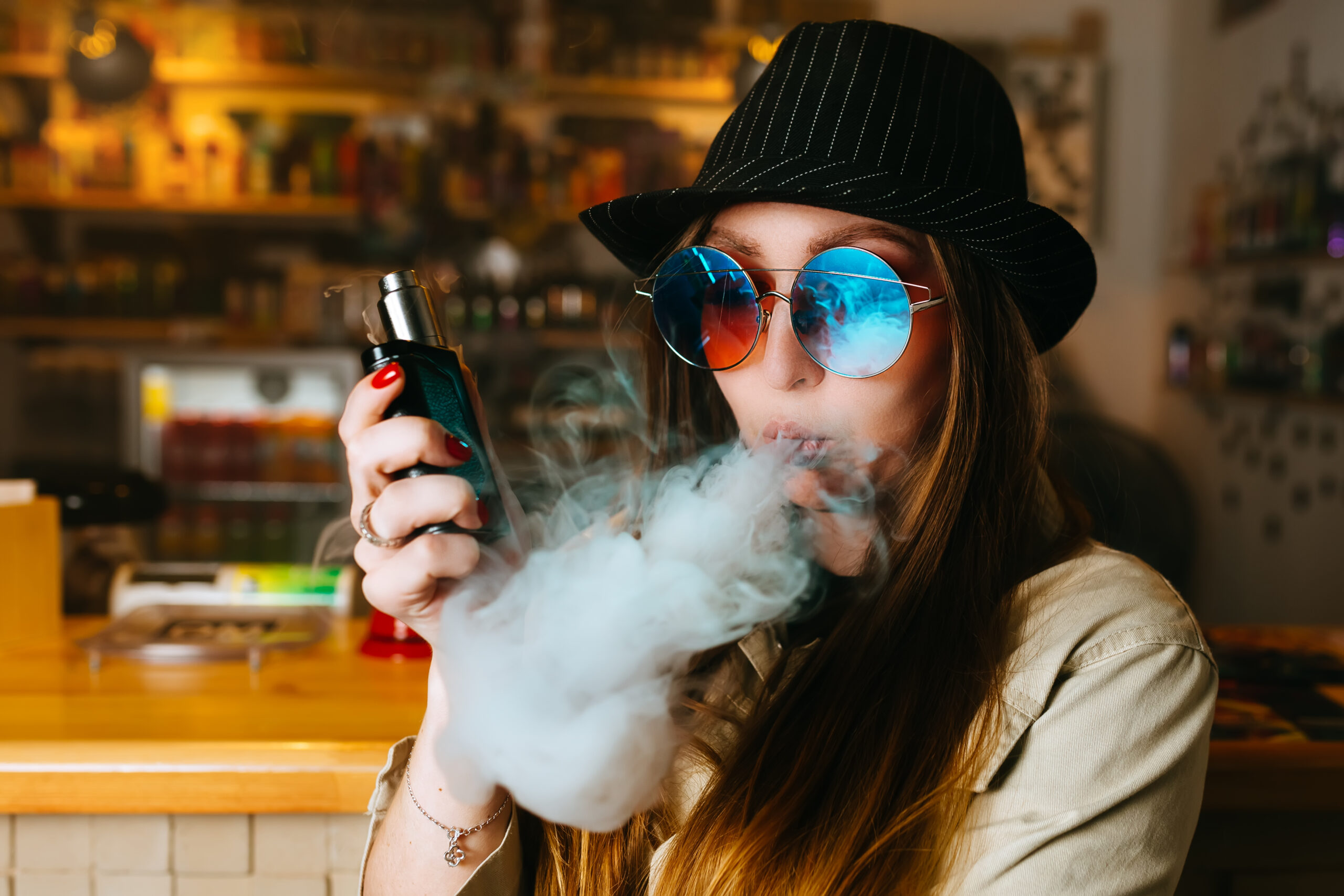 Vaping girl. Young hipster woman vape e-cig at the vapeshop.